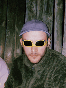 a man wearing sunglasses and a hat with the letter l on his shirt