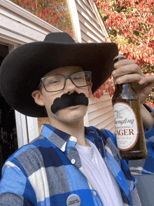 a man wearing a cowboy hat and glasses holds a bottle of longting lager