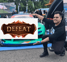 a man kneeling in front of a car with a defeat sign above him