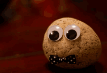 a rock with googly eyes and a bow tie on