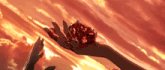 a person holding a red heart in their hand with a cloudy sky behind them