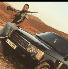 a man sitting on the hood of a black range rover