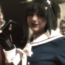 a woman in a sailor outfit holds a cell phone in her hand