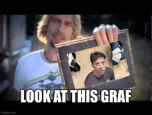 a man is holding up a picture of a boy with the caption look at this graf .