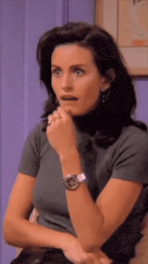 a woman wearing a watch and a ring on her finger looks surprised