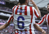 a soccer player wearing a red and white striped jersey with the number 6 on the back