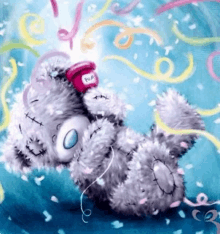 a teddy bear wearing headphones is laying on its back surrounded by confetti and ribbons .