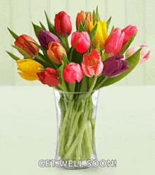 a vase filled with colorful tulips with the words get well soon on the bottom