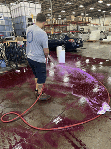 a man in a grey shirt is standing in a warehouse cleaning a floor