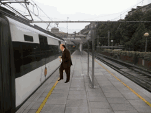 a man in a suit stands on a train platform with a sign that says ' barcelona ' on it