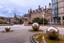 a large building with a fountain in front of it and a few balls in front of it