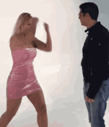 a woman in a pink dress is standing next to a man in jeans .