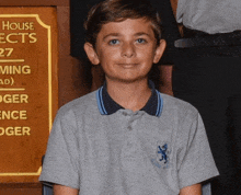 a young boy stands in front of a sign that says house ect 27