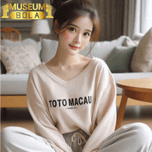 a woman wearing a toto macau sweater sits on the floor