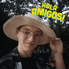 a man wearing a straw hat with the words hola amigos written above him