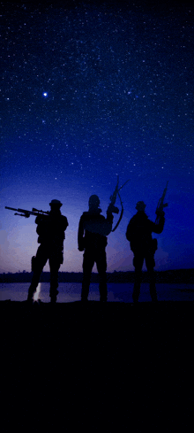 three soldiers are silhouetted against a starry blue sky