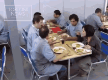 a group of people are sitting at a table with plates of food in front of a sign that says " torloni news "