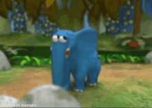 a blue elephant is standing on a grassy field in a video game .