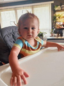 a baby in a striped shirt is sitting in a chair