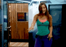 a woman in a green tank top stands in front of a plane