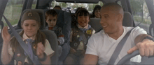 a group of children are sitting in the back seat of a car