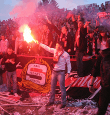 a man holding a flare in front of a banner that says sks start