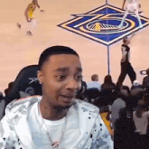 a man is sitting in a chair watching a basketball game on a computer screen .