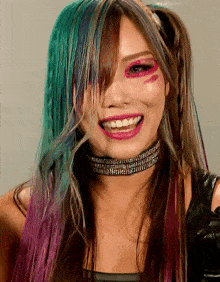 a woman with green and purple hair is smiling and wearing a choker with rhinestones