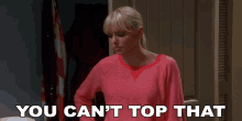 a woman in a pink sweater is standing in front of a door with the words " you can 't top that " above her