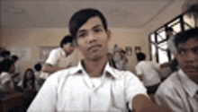 a man is sitting in a classroom with other students .