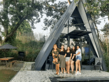 a group of women are posing in front of an a frame house