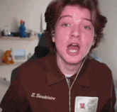 a young man wearing headphones and a brown shirt with the name t. baudelaine on it