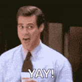 a man in a suit and tie is holding a cup of coffee and saying yay .