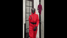 a person in a red squid game costume is standing in front of a door .