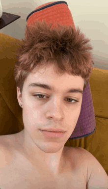 a young man with a hat on his head is sitting on a yellow couch