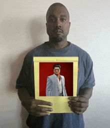 a man in a blue shirt is holding a piece of paper with a picture of a man in a suit on it