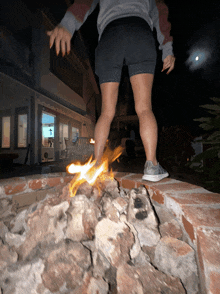 a woman in shorts is standing next to a fire pit