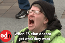 a woman wearing glasses and a black hat is screaming in front of a edn news banner