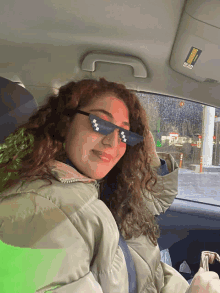 a woman wearing sunglasses is sitting in a car with a sticker on the visor that says warning