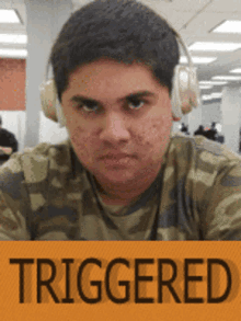 a man wearing headphones and a camo shirt has the word triggered on the bottom right