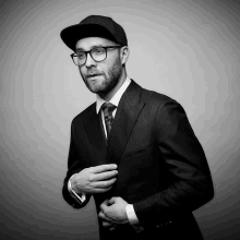 a man in a suit and hat adjusts his cufflinks