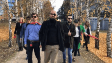 a group of people walking down a sidewalk with a man wearing a cape