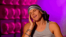 a man wearing a bandana and a tank top is rubbing his face