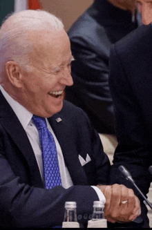 a man in a suit and tie laughs while shaking hands