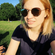 a woman wearing sunglasses and a blue shirt looks at the camera