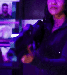 a woman is standing in front of a computer screen in a dark room holding a gun .