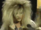 a woman in a wig is talking into a microphone in a dark room .