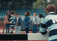 a group of young people are standing in a stadium and one of them has the number 11 on his back