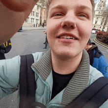 a young man taking a selfie with another man in a blue jacket