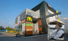 a man standing outside of a mcdonald 's with a sign that says mccafe